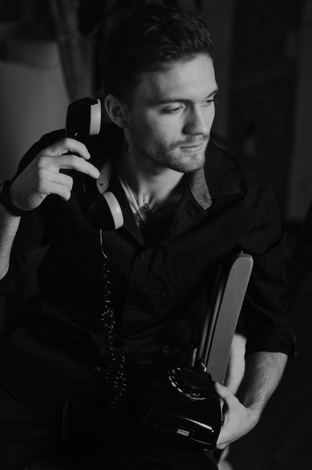 grayscale photo of man holding telephone